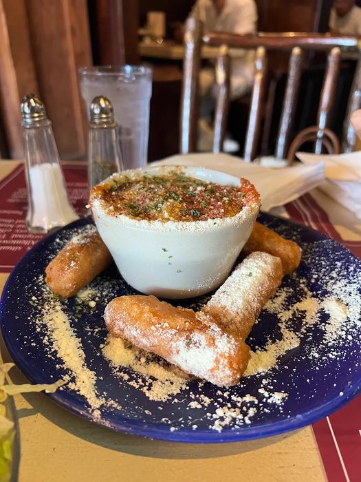 Golden fried mozzarella sticks served with a crock of marinara sauce and dusted with parmesan cheese on a blue plate at Gabriel's Gate Buffalo NY