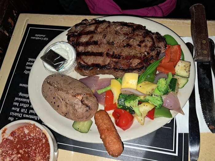 Gabriel's Gate N.Y. Strip steak plate from The Grill with baked potato, steamed mixed vegetables and onion ring garnish — Buffalo NY