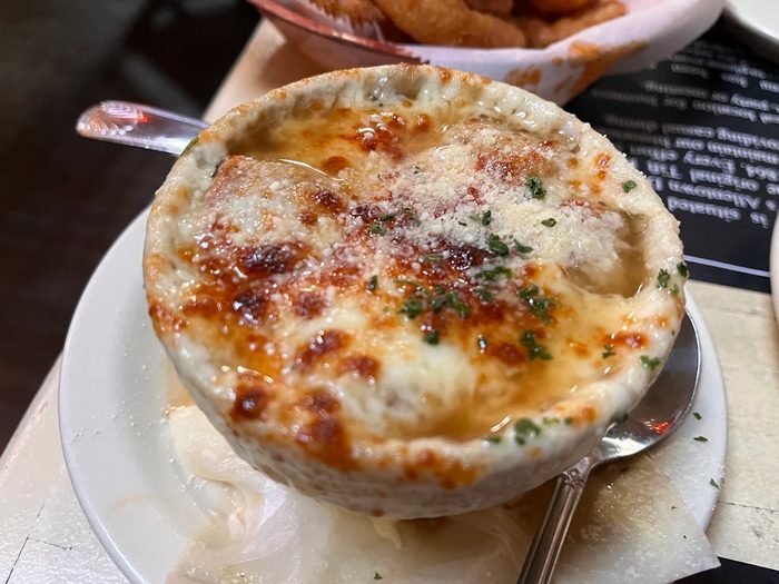 Gabriel's Gate signature French onion soup served in a white ceramic crock with broiled golden-brown provolone cheese crust on top — Buffalo NY award winner