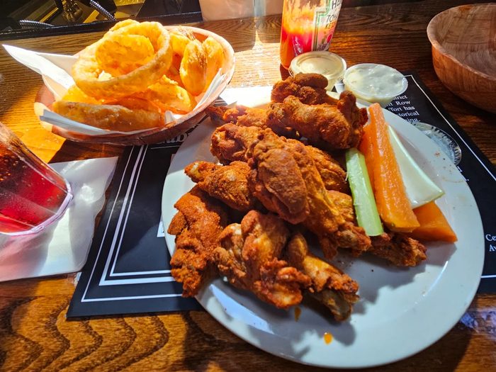 Crispy Buffalo chicken wings with golden onion rings, celery sticks, carrot sticks and bleu cheese dipping sauce served at Gabriel's Gate Buffalo NY