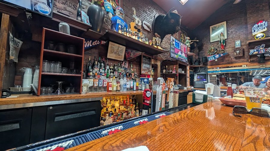 Gabriel's Gate bar interior showing the classic wooden bar, brick walls, mounted bison, Buffalo Bills memorabilia and vintage sports decor at 145 Allen Street Buffalo NY